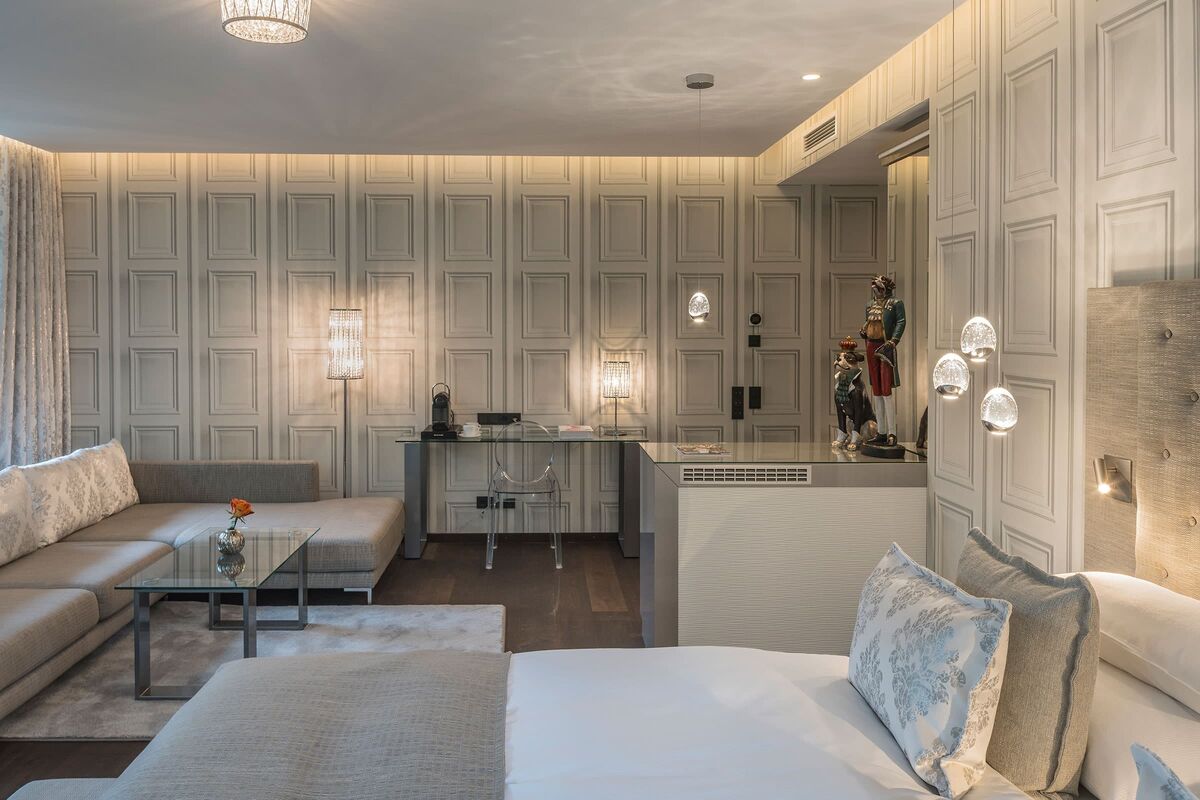 Stilvoll kombinierter Wohn- und Schlafbereich der Adler Suite mit Doppelbett, Sofa und Schreibtisch.